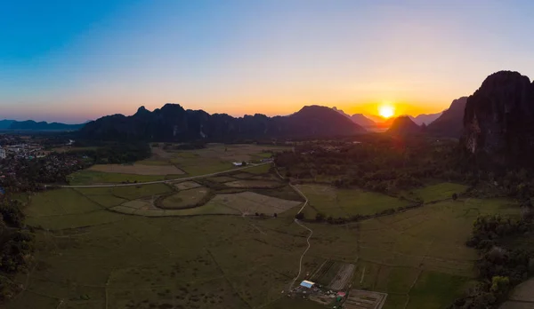 Hava: Vang Vieng backpacker seyahat hedef Laos, Asya. Günbatımı pirinç paddies Vadisi, peyzaj çarpıcı doğal kayalıklarla ve rock pinnacles, üzerinde. — Stok fotoğraf