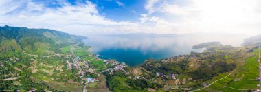 Hava: Toba Gölü ve Sumatra Endonezya 'dan Samosir Adası manzarası. Büyük volkanik kaldera suyla kaplı, geleneksel Batak köyleri, yeşil pirinç tarlaları, ekvatoral orman.