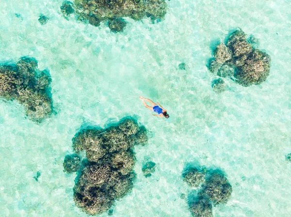 Aerial top down people snorkeling on coral reef tropical caribbean sea, turquoise blue water. Indonesia Wakatobi archipelago, marine national park, tourist diving travel destination