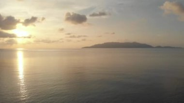 Hava: tropikal Hatta adası beyaz kum plaj Banda Adaları Maluku Endonezya yemyeşil orman turkuaz su mercan resif ilerler günbatımı gökyüzü üzerinde uçan. Yerli cinelike D-log renk profili