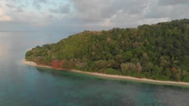 Hava: tropikal Hatta adası beyaz kum plaj Banda Adaları Maluku Endonezya yemyeşil orman turkuaz su mercan resif ilerler günbatımı gökyüzü üzerinde uçan. Yerli cinelike D-log renk profili