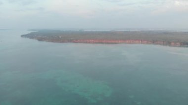 Hava: Ohoidertawun Kei Adaları Maluku Endonezya palmiye ağacı orman mercan resifi düşük gelgit kirlenmemiş sahil plaj gün batımı. Yerli cinelike D-log renk profili
