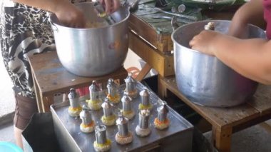 Geleneksel Güneydoğu Asya silindirli kek pişiren kadın, hindistancevizi unlu pirinç unlu palmiye şekerini metal tüplerde pişiriyor.