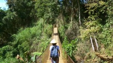 Tibet Köprüsü 'nde yürüyen geleneksel şapkalı kadın doğal park Kachanh Şelalesi' nde Banlung, Ratanakiri Kamboçya 'da seyahat ediyor.