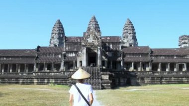 Angkor Wat seyahat hedef Kamboçya ziyaret eden bir turist. Tapınak harabelerine yürüyen geleneksel şapkalı kadın arka görüş.
