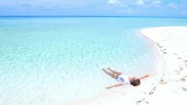 Yavaş hareket: turkuaz su beyaz kum plaj tropikal deniz ıssız ada Wakatobi Endonezya cennet seyahat hedef güneşli sıcak gün rahatlatıcı kadın güneşleniyor