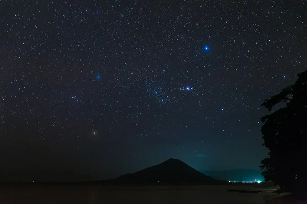 Orion constellation starry sky stars over Gunung Api volcanic island glowing in tropical night Indonesia Banda Islands Moluccas Maluku