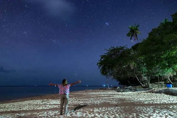 Mulher olhando para as estrelas e caminho leitoso na praia de areia, luz da tocha no céu noturno, visão traseira, pessoas reais. Indonésia, ilhas Kei, Molucas Maluku — Fotografia de Stock