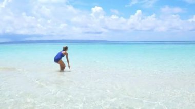 Turkuvaz suda yürüyen bir kadın. Beyaz kum kumsalı tropikal deniz adası Wakatobi Endonezya cennet seyahati. Güneşli bir gün.