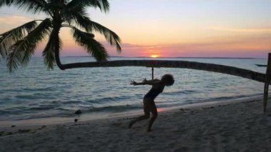 Günbatımında tropikal sahilde modern dans eden kadın palmiye ağacı Wab Kei Adaları Moluccas Maluku Endonezya ilham verici seyahat merkezi