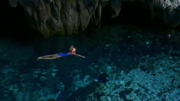 慢动作 女人在山洞内的天然湖中游泳 五颜六色的反射 碧绿透明的水 夏季冒险 旅游目的地 摩鹿卡岛 印度尼西亚 — 图库视频影像