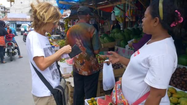 トゥアル インドネシア 2018年10月頃 トゥールケイ諸島モルッカスインドネシアの通りで食品市場でベンダーにお金を払う外国人女性 — ストック動画