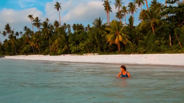 ターコイズブルーの水の中の女性日光浴白い砂浜熱帯海岸線パシルパンジャンケイ島インドネシアの楽園旅行先日没の光 — ストック動画