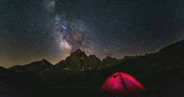Zaman atlamalı Samanyolu galaksi yıldızları Alpler üzerinde dönen, Kamp ışıklı çadır, karla kaplı dağ zirvesi, astro gece gökyüzü yıldız seyir