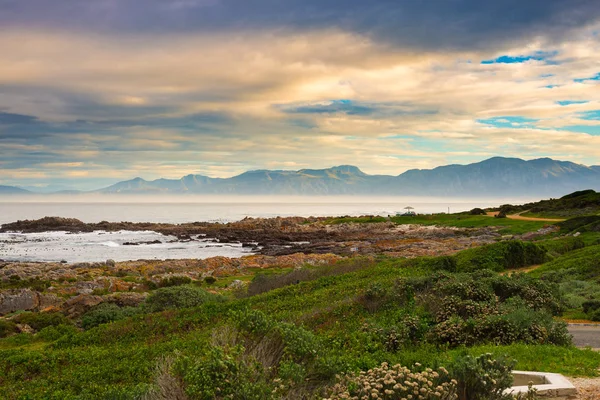 Linha costeira rochosa no oceano em De Kelders, África do Sul, famosa pela observação de baleias. Estação de inverno, céu nublado e dramático . — Fotografia de Stock