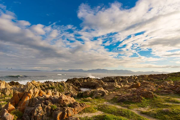Linha costeira rochosa no oceano em De Kelders, África do Sul, famosa pela observação de baleias. Estação de inverno, céu nublado e dramático . — Fotografia de Stock