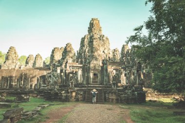 Bayon Tapınağındaki kadın taş suratlara bakıyor Angkor Thom, sabah açık mavi gökyüzü. Budizm meditasyon konsepti, dünyaca ünlü seyahat merkezi, Kamboçya turizmi. Renkli bağ bozumu