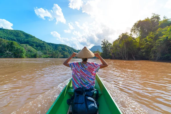 ラオスのナムオウ川の茶色の水に伝統的な帽子の巡航を持つ女性、東南アジアで有名な風景山のジャングルの有名な旅行先リアビュー — ストック写真
