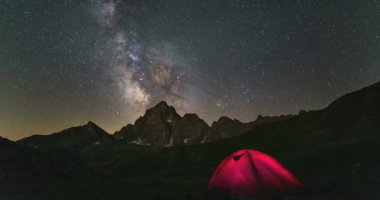 Zaman atlamalı Samanyolu galaksi yıldızları Alpler üzerinde dönen, Kamp ışıklı çadır, karla kaplı dağ zirvesi, astro gece gökyüzü yıldız seyir