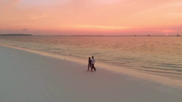 夕暮れ時にロマンチックなドラマチックな空とエキゾチックなビーチを歩くカップルインドネシアモルッカスマルクインドネシア 旅行人カップル関係コンセプト — ストック動画