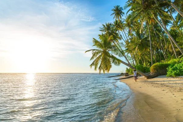 Frau mit traditionellem asiatischen Hut entspannt sich am tropischen Strand unter einer Kokospalme im Gegenlicht Sonnenuntergang echte Menschen. Indonesien, Banyak-Inseln, Reiseziel Sumatra. — Stockfoto