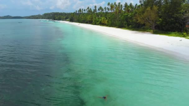夕日の白い砂浜の熱帯海岸線でターコイズブルーの水で泳ぐ女性パシルパンジャンケイ諸島インドネシアの楽園の旅行先 — ストック動画