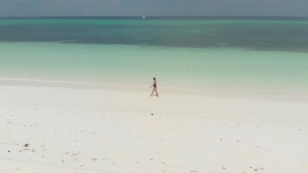Воздушный Женщина Прогуливающаяся Белому Песчаному Пляжу Бирюзовой Водой Вдоль Побережья — стоковое видео
