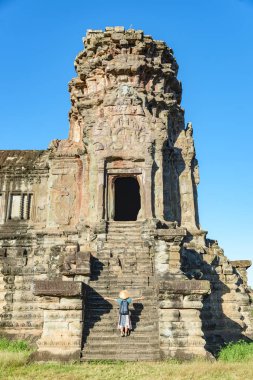 Güneş doğarken bir turist Angkor Wat ziyaret kalıntıları, hedef Kamboçya seyahat. Geleneksel şapka ve yükseltilmiş kollar, kadın ile arka görünümü, ana cephe merdiven kapısı ve kuleleri.