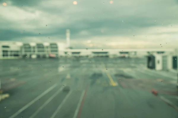 Rain drops on window of airport, monsoon season in South East Asia. Blurred aircraft and terminal. Transportation weather concept. — Stock Photo, Image