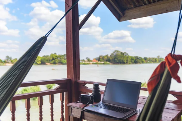 Mekong Nehri, Laos üzerinde asılı hamak ile turistik tatil ahşap balkonda dizüstü bilgisayar ile çalışma. Dünya çapında çalışan bin yıllık kavram ve dijital göçebeler. — Stok fotoğraf