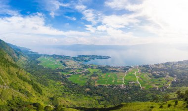Hava: Toba Gölü ve Sumatra Endonezya 'dan Samosir Adası manzarası. Büyük volkanik kaldera suyla kaplı, geleneksel Batak köyleri, yeşil pirinç tarlaları, ekvatoral orman.