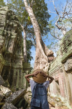 Orman ortasında Angkor harabeleri ziyaret eden bir turist, Angkor Wat tapınak kompleksi, seyahat hedef Kamboçya. Geleneksel şapkalı kadın, arka görüş.