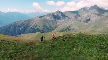 Havadan yavaş çekim: dağ tepesinde yürüyüş çift backpackers, doğal manzara. Alpler'de yaz maceraları. Fetih başarı olgun yetişkin eğlenceli refah fitness sahip