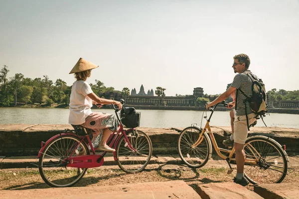 Pareja turística en bicicleta en el templo de Angkor, Camboya. La fachada principal de Angkor Wat se refleja en el estanque de agua. Eco turismo amigable viajar. Tonificado — Foto de Stock
