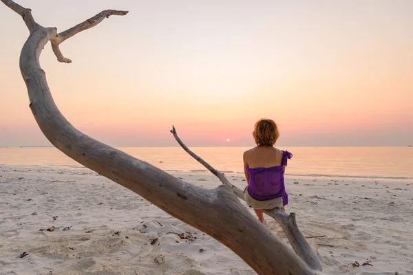 Uma pessoa sentada na areia ramo praia céu romântico ao pôr do sol, silhueta vista traseira, luz solar dourada, pessoas reais. Indonésia, ilhas Kei, Molucas Maluku — Fotografia de Stock