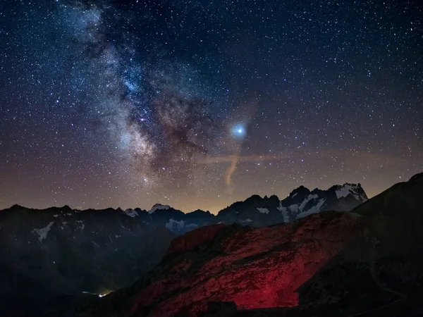 The Milky Way and starry sky on the Alps, Massif des Ecrins, Briancon Serre Chevalier ski resort, France. Panoramic view high mountain range and glaciers, astro photography, stargazing. Planet Jupiter