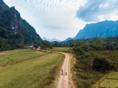 Hava: Laos Asya kaya doruklarına yeşil vadi dramatik gökyüzü Vang Vieng backpacker seyahat hedef etrafında doğal manzara toprak yolda dağ bisikleti sürme turist çift