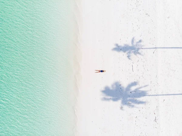 Aerial top down view tropical beach caribbean sea. Woman sunbathing between palm tree shade on white sand beach turquoise water. Travel exotic vacation. — Stock Photo, Image