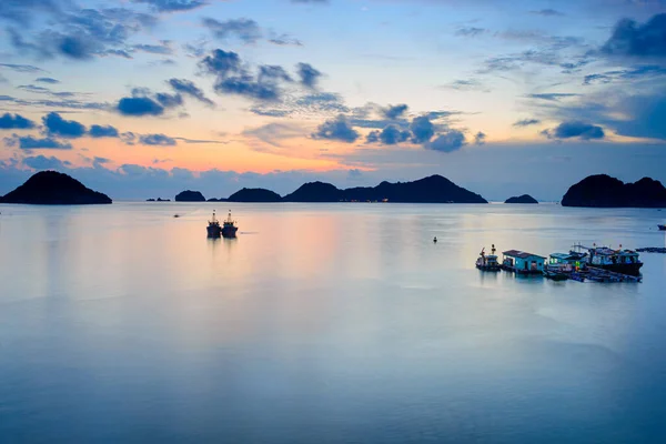 Vietnã Cat Ba baía ao pôr do sol com barcos de pesca flutuantes no mar, nebulosidade clima tropical, céu colorido e perfil ilhas no horizonte. Exposição longa — Fotografia de Stock