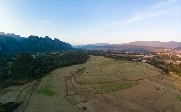 Aerial: Vang Vieng zaino in spalla destinazione di viaggio in Laos, Asia. Tramonto su scogliere panoramiche e pinnacoli rocciosi, valle delle risaie, paesaggio mozzafiato . — Foto Stock