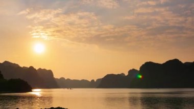 Zaman aşımı: Vietnam 'daki ünlü turizm merkezi Cat Ba Adası' ndan Ha Long Bay manzaralı gün batımı. Bulutlu manzaralı gökyüzü, ufuktaki denizde kireçtaşı kaya zirveleri.