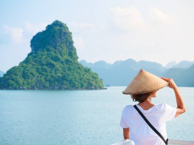 Geleneksel bakış açısı olan kadın Halong Körfezi, Vietnam. Ha Long Körfezi kaya zirvelerinde seyahat eden bir turist. Beyaz kadın ünlü şehir simgesinde tatilde eğleniyor..