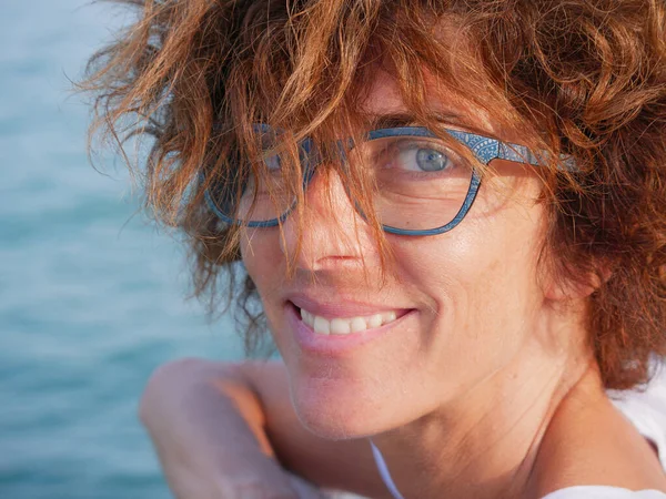 Portrait lady with blue eyes and glasses at sea. Smiling woman on cruise vacation, real people traveling, outdoors natural sunlight, relax city break concept.