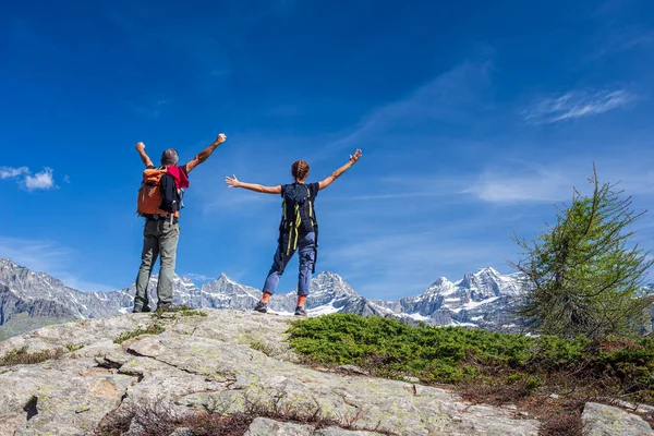 双手伸展在山顶上的夫妇 两个人在观景高山景观暑假健身自由的概念 — 图库照片