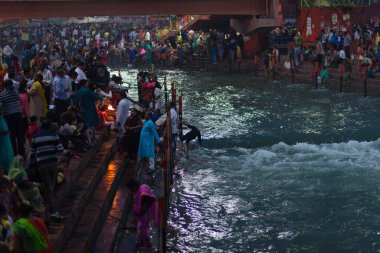 Haridwar, Hindistan - 20 Mart 2017: Haridwar, Hindistan 'da kutsal ghat, Hindu dini için kutsal kasaba. Hacılar Ganj Nehri 'ne çiçekler ve yanan mumlar sunuyor..