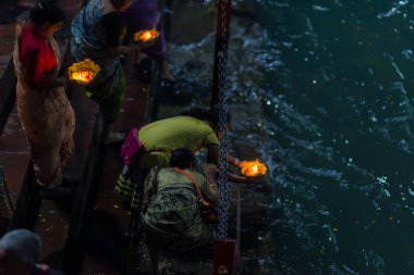 Haridwar, Hindistan - 20 Mart 2017: Haridwar, Hindistan 'da kutsal ghat, Hindu dini için kutsal kasaba. Hacılar Ganj Nehri 'ne çiçekler ve yanan mumlar sunuyor..