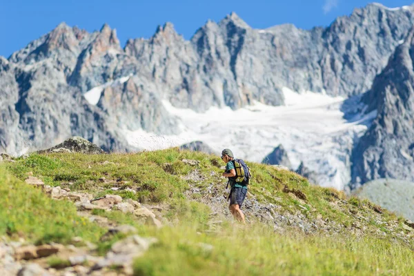 Sırt çantalı bir kadın dağın tepesine doğru yürüyor, manzaralı buzullar ve dramatik manzaralar yaz sporları seçici dikiz manzarası, özgürlük konsepti.