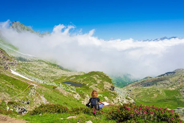 女人在山上的自然环境中沉思 一个人坐在荷花丛中摆姿势 绿谷和云彩景观 — 图库照片