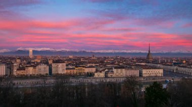 Zaman aşımı: Torino Italia 'da gün doğumu (Torin, İtalya). Ufuk çizgisi ve binaların üzerindeki Köstebek Antonelliana kulesi. Arkaplanda renkli dramatik gökyüzü ve dağ aralığı (Alpler)