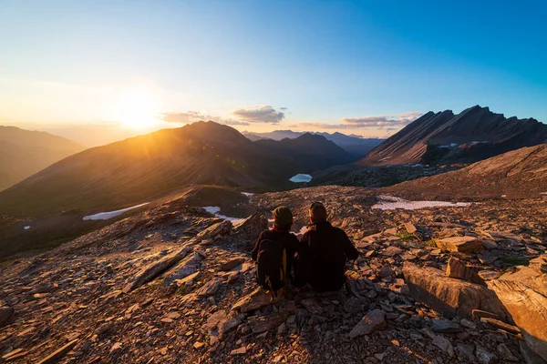 有几个徒步旅行者从山顶眺望阳光 男子和女子在风景秀丽的高山风景中度假 夏季活动健康幸福自由 — 图库照片